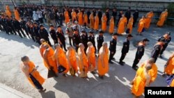 Polisi dan biksu Buddhis berjalan memasuki vihara Dhammakaya untuk mencari biksu Buddhis yang menjadi buron di provinsi Pathum Thani, Thailand (17/2). (foto: REUTERS/Chaiwat Subprasom)