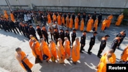 Policemen and Buddhist monks walk inside Dhammakaya temple to search for a fugitive Buddhist monk in Pathum Thani province, Thailand, Feb. 17, 2017.