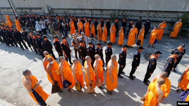 Policemen and Buddhist monks walk inside Dhammakaya temple to search for a fugitive Buddhist monk in Pathum Thani province, Thailand, Feb. 17, 2017.