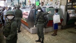 Soldados con mascarillas protectoras como medida preventiva contra la propagación del nuevo coronavirus, patrullan dentro de un mercado en Caracas, Venezuela.