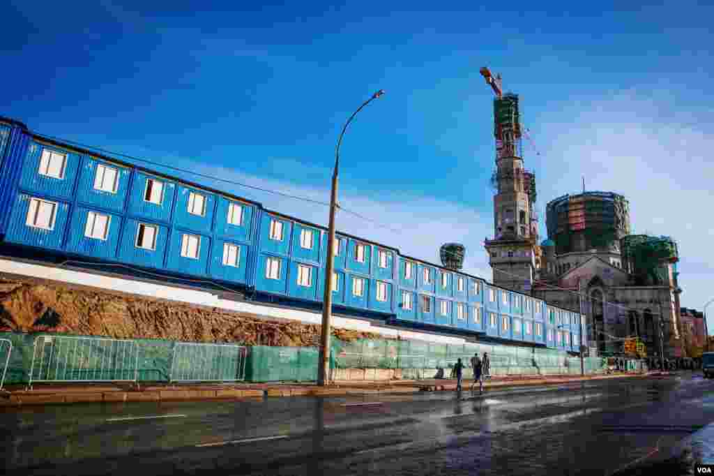 Blue construction workers barracks stand next to the concrete shell of the Cathedral Mosque which is to be completed by 2015, Moscow. (Vera Undritz for VOA)