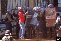 FILE - Armed Zimbabwean Riot Police confront a protester during a demonstration in Harare, August, 26, 2016.