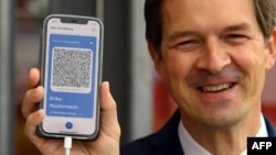 Ronald Fritz, project manager at IBM, presents a mobile phone with the model of a digital vaccination passport (CovPass) during a media event at the Babelsberg vaccination centre in Potsdam near Berlin, northeastern Germany, on May 27, 2021