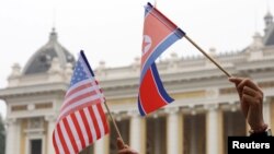 Warga memegang bendera AS dan Korea Utara di Hanoi, Vietnam, 28 Februari 2019. (Foto: REUTERS/Kham)