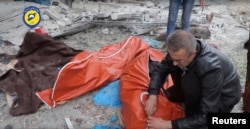 A man wraps a body in a street of rebel-held eastern Aleppo after artillery bombardment, which rescue workers say has killed at least 45 people, mostly women and children, Syria, in this still image taken on Nov. 30, 2016 from a social media website obtained by Reuters.