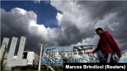 Un hombre pasa junto a una bandera argentina pintada con la leyenda "Fuerza argentinos", frente a la base naval en Mar del Plata hacia donde se dirigía el submarino ARA San Juan antes de desaparecer. Fotografía tomada el 20 de noviembre de 2017. 