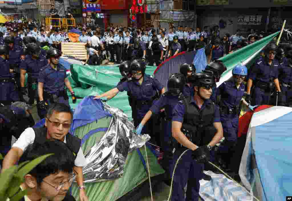 Polisi memindahkan tenda-tenda yang dipasang oleh para demonstran ketika mereka mengosongkan lokasi yang diduduki di distrik Mong Kok, Hong Kong, 26 November 2014.