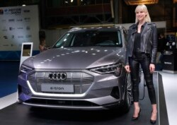 A model stands next of the new electric Audi e-tron Quatro, which display at the e-Motor show, in Beirut, Lebanon, Thursday, April 11, 2019.