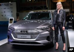 A model stands next of the new electric Audi e-tron Quatro, which display at the e-Motor show, in Beirut, Lebanon, Thursday, April 11, 2019.