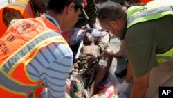 United Nations and other workers assist a young wounded man after he and others were airlifted to Mogadishu for treatment, following Sunday's attack on restaurants in the city of Baidoa, at the airport in Mogadishu, Somalia, Feb. 29, 2016. 