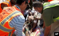 United Nations and other workers assist a young wounded man after he and others were airlifted to Mogadishu for treatment, following Sunday's attack on restaurants in the city of Baidoa, at the airport in Mogadishu, Somalia, Feb. 29, 2016.