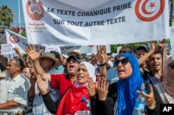 People demonstrate with a banner reading "Quran text before any other text" during a demonstration in Tunis, Aug 11, 2018.