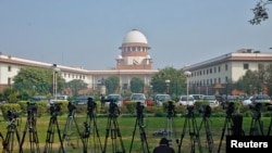 FILE - A television journalist sets his camera outside the Supreme Court in New Delhi.