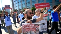 Activists, one holding today's copy of the Cumhuriyet newspaper, march to a court in Istanbul, July 24, 2017, protesting against the trial of journalists and staff from the newspaper, accused of aiding terror organizations. 