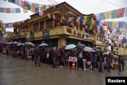 FILE - People stand in rain as they wait to welcome Tibetan spiritual leader Dalai Lama in Bomdila in the northeastern state of Arunachal Pradesh, India, April 4, 2017.