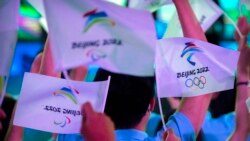 FILE - Participants wave flags with the logos of 2022 Beijing Winter Olympics and Paralympics before a launch ceremony to reveal the motto for the Winter Olympics and Paralympics in Beijing, Sept. 17, 2021.