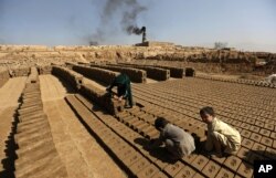 FILE - Afghan children help their father's work at a local brick factory on the outskirts of Kabul, Sept. 19, 2016.