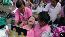 Seorang warga menangis saat doa bersama diadakan di depan rumah sakit Siriraj, tempat Raja Bhumibol Adulyadej dirawat di Bangkok, Thailand (13/10).