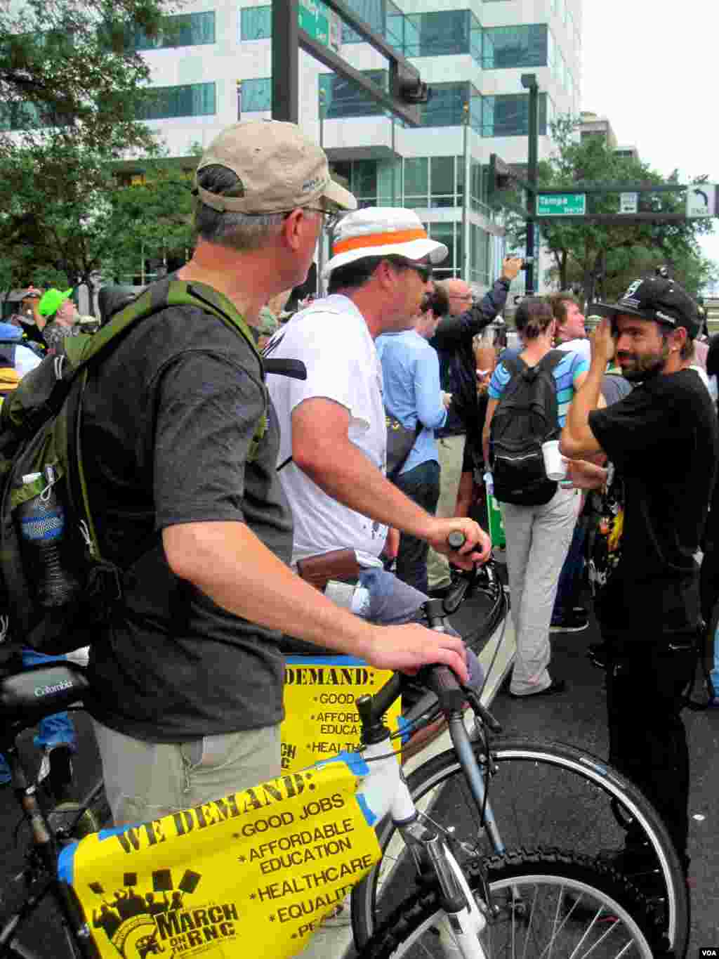 Para demonstran dari kelompok Occupy Tampa menggelar aksi protes di dekat arena Konvensi Nasional Partai Republik, Tampa, Florida, Senin. Berbagai tuntutan mereka tertera di poster yang dipasang di samping sepeda mereka (Eva Mazrieva/VOA). 