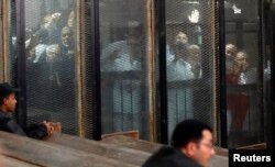 FILE - Muslim Brotherhood members are seen behind bars during a court session in Cairo, Egypt, Dec. 2, 2018.