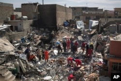FILE - Civil protection rescue teams work on the debris of a destroyed house to recover the body of people killed during fighting between Iraqi security forces and Islamic State militants on the western side of Mosul, Iraq, March 24, 2017.