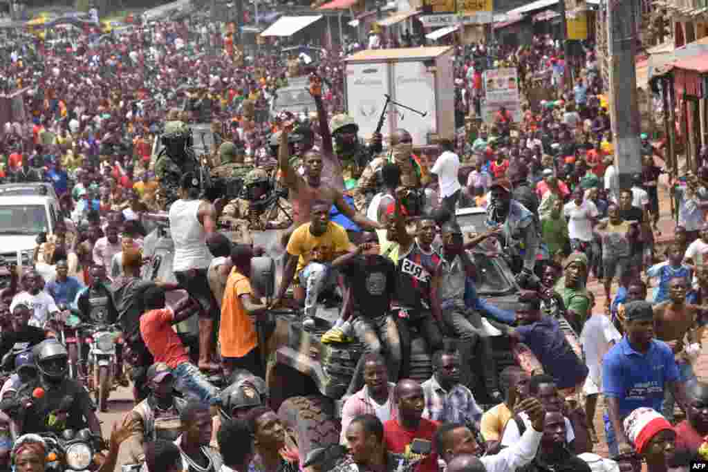 People celebrate in the streets with members of Guinea&#39;s armed forces after the arrest of President Alpha Conde in a coup d&#39;etat in Conakry, Sept. 5, 2021.