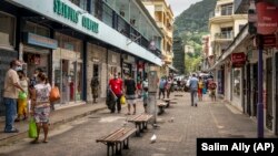 Des piétons portent des masques lorsqu'ils marchent dans une rue de la capitale Victoria, île de Mahé, Seychelles le 25 février 2021.