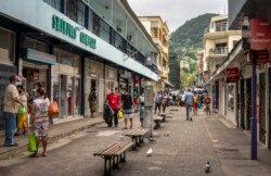 Pejalan kaki mengenakan topeng saat mereka berjalan di jalan di ibu kota Victoria, Pulau Mahe, Seychelles, Kamis, 25 Februari 2021. (Foto: AP/Salim Ally)