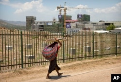 In this Nov. 14, 2018, photo, a woman carrying a bundle of sticks on her head walks past a building being built by Chinese state-owned construction firm China Railway Group Limited in Port Moresby, Papua New Guinea.