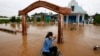 A Cambodian woman pushes a church gate with an oar to steer her wooden boat in a flooded area along the Mekong river in Koh Phos village, Kandal province near Phnom Penh, Cambodia, Sunday, Sept. 29, 2013. (AP Photo/Heng Sinith)