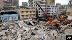 Rescuers using mechanical diggers remove rubble from the site of a collapsed building in downtown Dar es Salaam, Tanzania, Mar. 29, 2013.