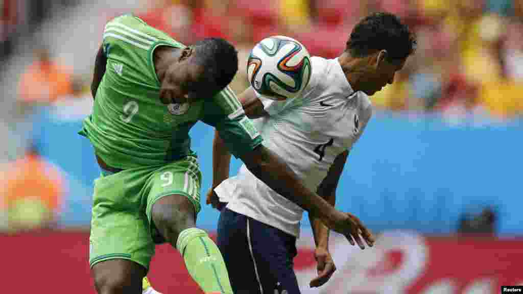 France's Raphael Varane is hit by the ball in the face beside Nigeria's Emmanuel Emenike.