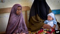 A Somali mother and her older child wait in line for her baby to receive a five-in-one vaccine against several potentially fatal childhood diseases, at the Medina Maternal Child Health center in Mogadishu, Somalia Wednesday, April 24, 2013. (AP Photo/Ben) 
