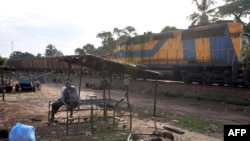 Les habitants de Kamsar sont assis à proximité d'un train tirant une centaine de wagons chargés de bauxite, en Guinée, le 24 octobre 2008.