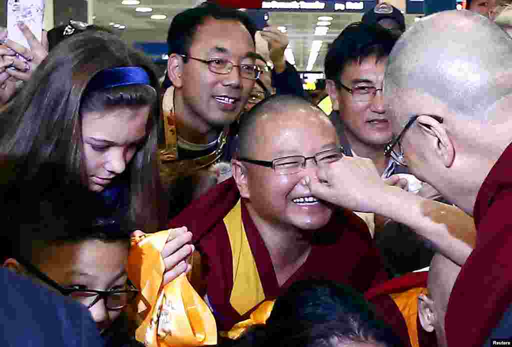 Exiled Tibetan spiritual leader the Dalai Lama (C) pinches the nose of a supporter after arriving at Sydney International airport at the start of a 12-day visit to Australia.