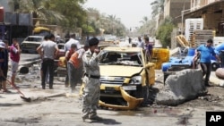 People inspect the aftermath of a car bomb attack in Baghdad's Shiite enclave of Sadr City, Iraq, July 23, 2012.