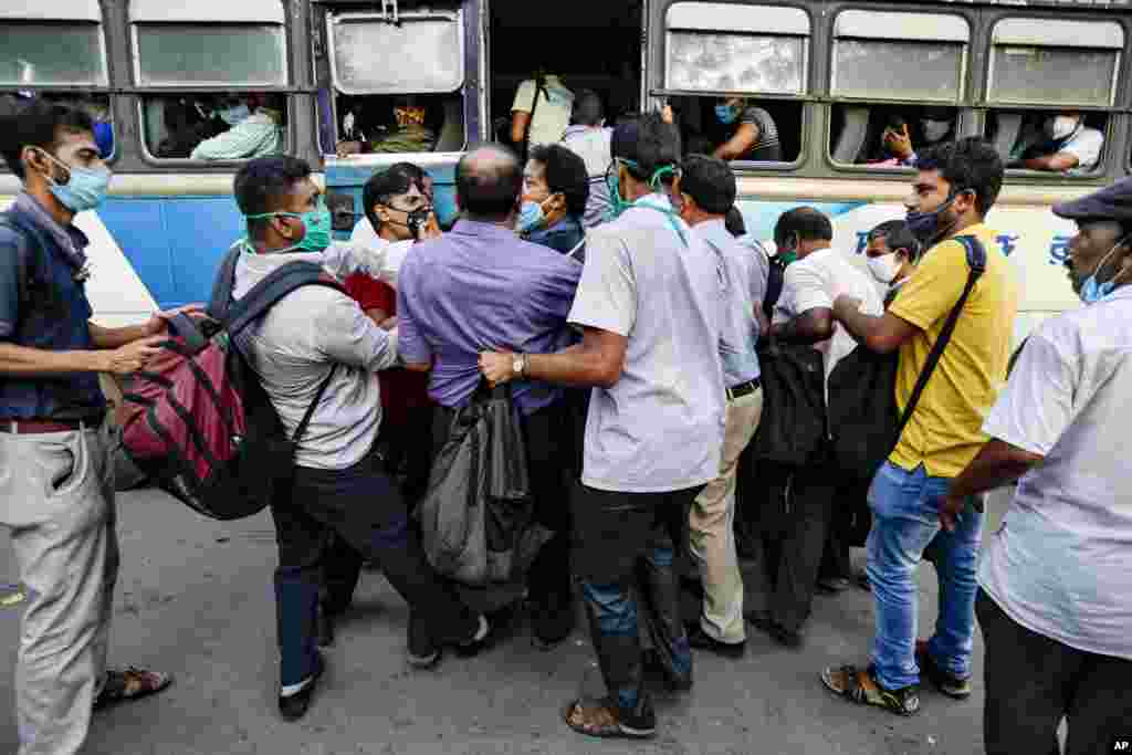 People ignoring physical distancing norms push each other to get on a bus in Kolkata, India.