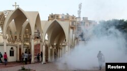 Coptic Christians run inside the main cathedral in Cairo as police fire tear gas during clashes with Muslims standing outside the cathedral April 7, 2013.