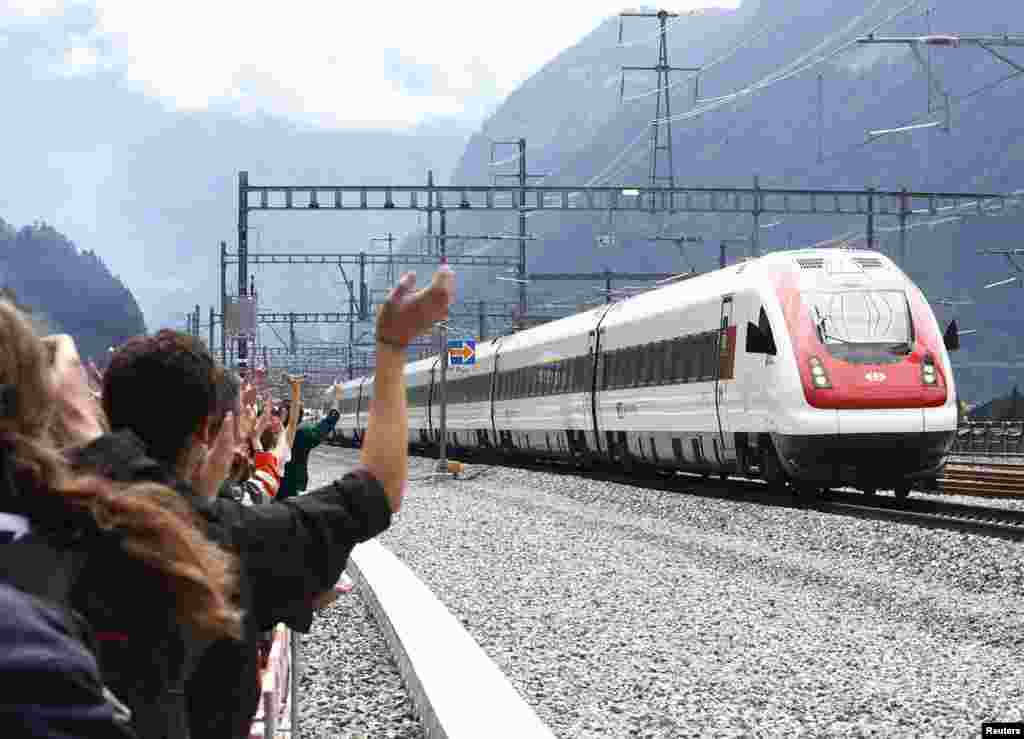 Guests wave at a train that has passed through a new tunnel during the opening ceremony of the NEAT Gotthard Base Tunnel, the world's longest and deepest rail tunnel, near the town of Erstfeld, Switzerland. The 57.1-km (35.5 mile)-long Gotthard Base Tunnel, 17 years under construction and designed to last a century, is part of a 23 billion Swiss franc ($23.1 billion) infrastructure project to speed passengers and cargo by rail below the Alps, as much as 2.3 km (1.7 miles) under the mountain chain, which divides Europe's north and south.