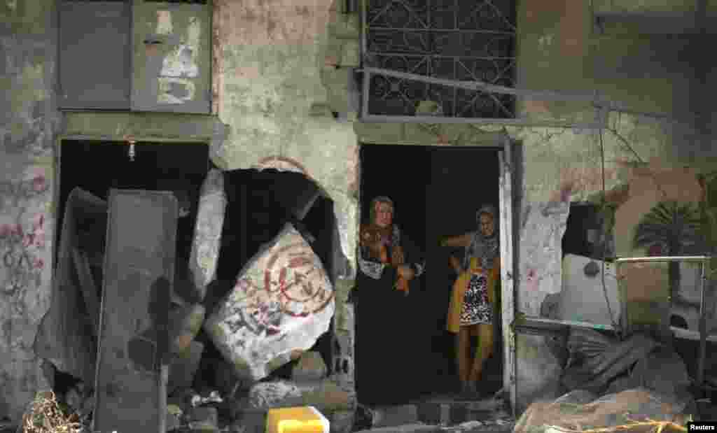 Two women stand in the doorway of the damaged house they returned to it during a 72-hour truce in Beit Hanoun town, in the northern Gaza Strip, Aug. 11, 2014.