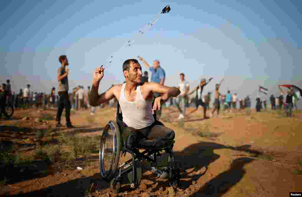 A disable Palestinian uses a sling to hurl stones at Israeli troops during a protest demanding the right to return to their homeland at the Israel-Gaza border, in Gaza.
