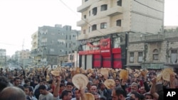 Protesters with pieces of bread shout slogans during a demonstration to show their solidarity with the protesters in Daraa, in the Syrian port city of Banias, May 3, 2011