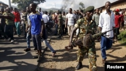 A soldier walks away from protesters in Burundi's capital, Bujumbura, as they clash with riot police. Monday was the second day of demonstrations against the president's decision to run for a third term, a move critics say violates the constitution.