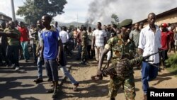 A soldier walks away from protesters in Burundi's capital, Bujumbura, as they clash with riot police. Monday was the second day of demonstrations against the president's decision to run for a third term, a move critics say violates the constitution.