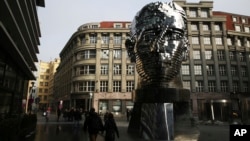 FILE - Tourists walk past a moving metal sculpture of writer Franz Kafka in his birth city of Prague, Czech Republic, Feb. 4, 2017. 