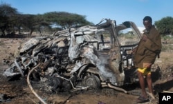 FILE - A Somali soldier stands near a vehicle destroyed by a suicide car bomb attack near the Elasha Biyaha settlement south of Mogadishu, Somalia — an attack that followed the killing of al-Shabab's top leader in a U.S. airstrike, Sept. 8, 2014.