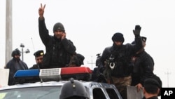 Cảnh sát chống bạo động Iraq giơ dấu hiệu chiến thắng trên đường trở về trụ sở sau vụ đụng độ với al-Qaida tại Basra, ngày 5/1/2014. 