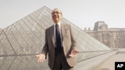 FILE - Chinese American architect I.M. Pei bursts out laughing while posing in front of the Louvre glass pyramid, in the museum's Napoleon Courtyard, prior to its inauguration by French President Francois Mitterrand on Wednesday, Mar. 29, 1989 in Paris. (AP Photo/Pierre Gleizes)