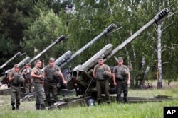 FILE - Members of a rapid reaction unit of Ukraine’s National Guard stand in front of howitzers during a ceremony marking the first anniversary of its creation, in the village of Stare, 80 km east of Kyiv, Ukraine, June 2, 2016.