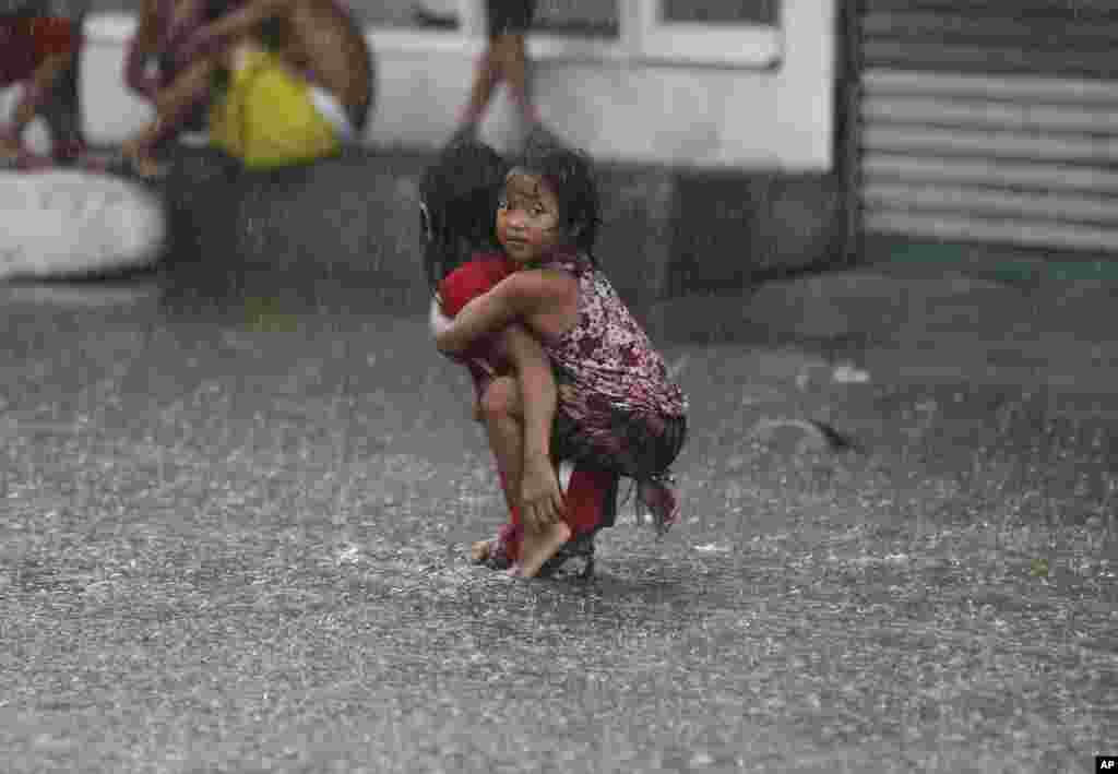 A Filipino girl is carried along a flooded road in suburban Mandaluyong, east of Manila, Philippines, as monsoon downpours intensify while Typhoon Nepartak exits the country.